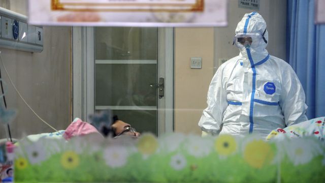 Seorang dokter mengenakan pakaian pelindung merawat warga yang terkena virus corona. (Foto: Chinatopix via AP/Kumparan.com)