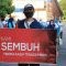 Seorang warga yang dinyatakan sembuh dari Covid-19 membawa spanduk bertuliskan ucapan terima kasih kepada tenaga medis saat dipulangkan dari tempat karantina di Asrama Haji Surabaya, Jumat (5/6/2020). (HUMAS PEMKOT SURABAYA) (Foto: Kompas.com)